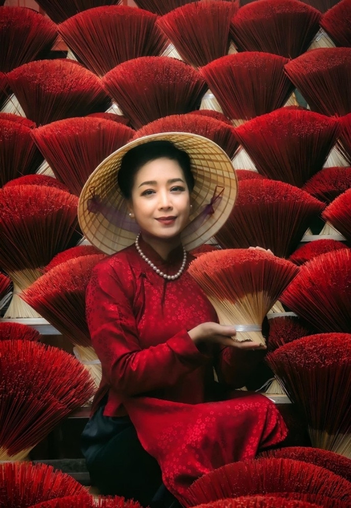 NSƯT Chiều Xuân diện áo dài đỏ, chụp ảnh bên những bó hương tại làng nghề truyền thống ở Hà Nội.