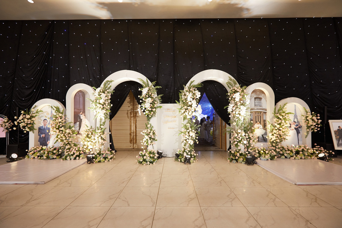 Lối cổng vào tiệc được kết hoa, xung quanh là ảnh cưới của cô dâu và chú rể. Để ghi lại hành trình hơn một thập kỷ bên nhau, Khánh Thi - Phan Hiển đã thực hiện khoảng 10 bộ ảnh cưới, được chụp tại nhiều quốc gia như Pháp, Thụy Sĩ... Bộ hình ở Pháp tái hiện khoảnh khắc khiêu vũ của họ.