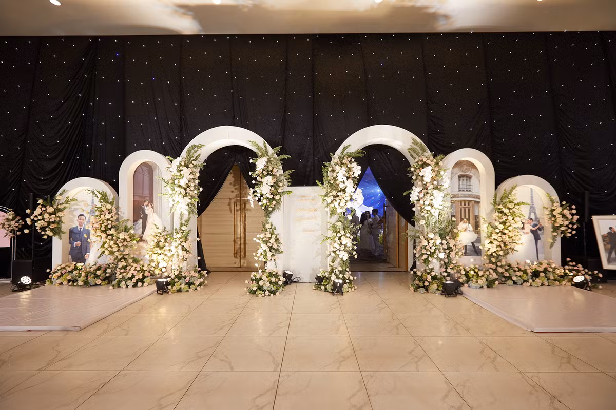 Lối cổng vào tiệc được kết hoa, xung quanh là ảnh cưới của cô dâu và chú rể. Để ghi lại hành trình hơn một thập kỷ bên nhau, Khánh Thi - Phan Hiển đã thực hiện khoảng 10 bộ ảnh cưới, được chụp tại nhiều quốc gia như Pháp, Thụy Sĩ... Bộ hình ở Pháp tái hiện khoảnh khắc khiêu vũ của họ.