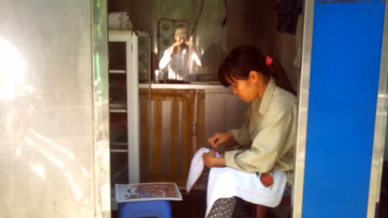 Tận dụng thời gian, nhân viên nhà vệ sinh thêu thùa chờ khách đến.