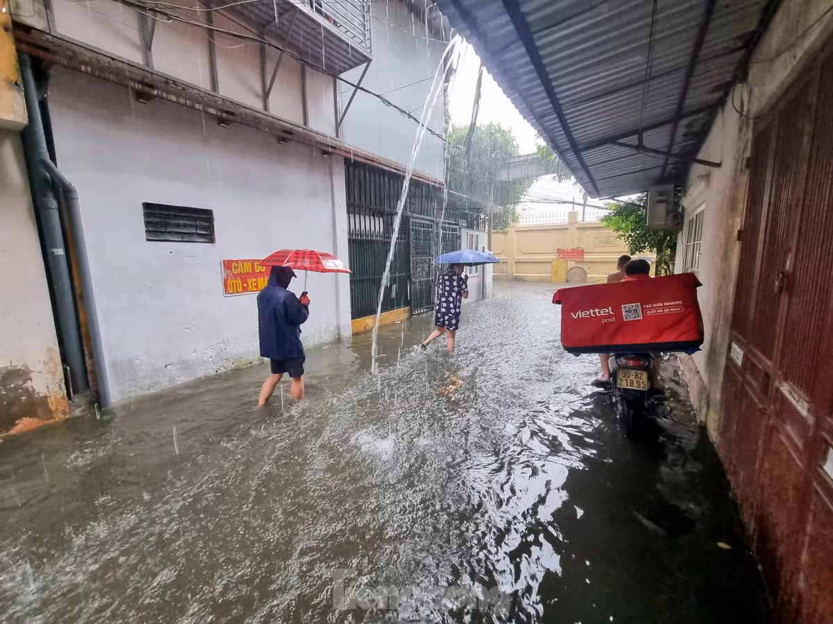 Người dân bì bõm lội nước, nhiều gia đình phải di chuyển xe máy đi gửi chỗ cao hơn.