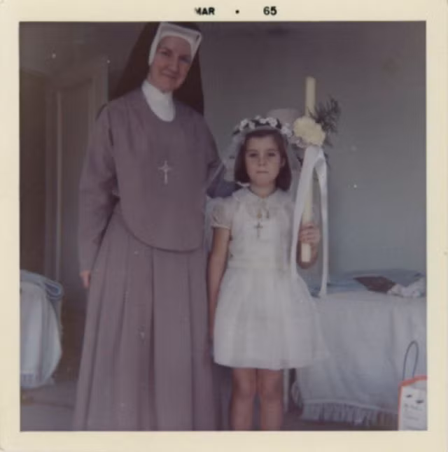 Caroline Kennedy đứng bên một bà sơ khi làm phù dâu tại một đám cưới ở nhà thờ, tháng 3/1965.