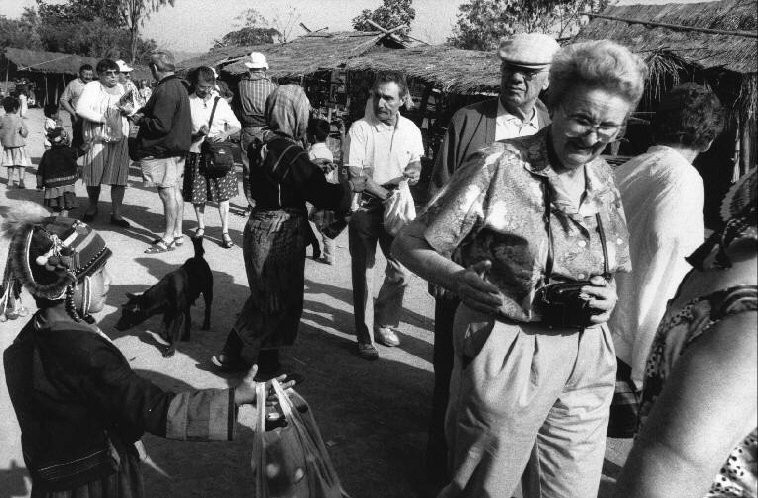 Khách du lịch phương Tây thăm một ngôi làng của người Akha ở vùng Tam Giác Vàng. Một phần nguồn thu từ du lịch sẽ được người dân ở đây dùng để thỏa mãn cơn nghiện ma túy. Ảnh: Patrick Zachmann/ Magnum.