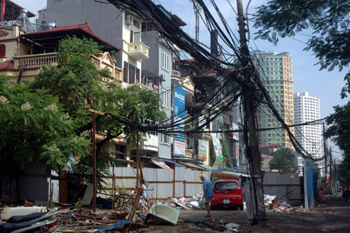Làm giá đỡ dây diện, cáp viễn thông bên đường Nguyên Hồng, quận Ba Đình. Người dân khu vực này có thể gặp nguy hiểm nếu đường dây dẫn điện bị hở.