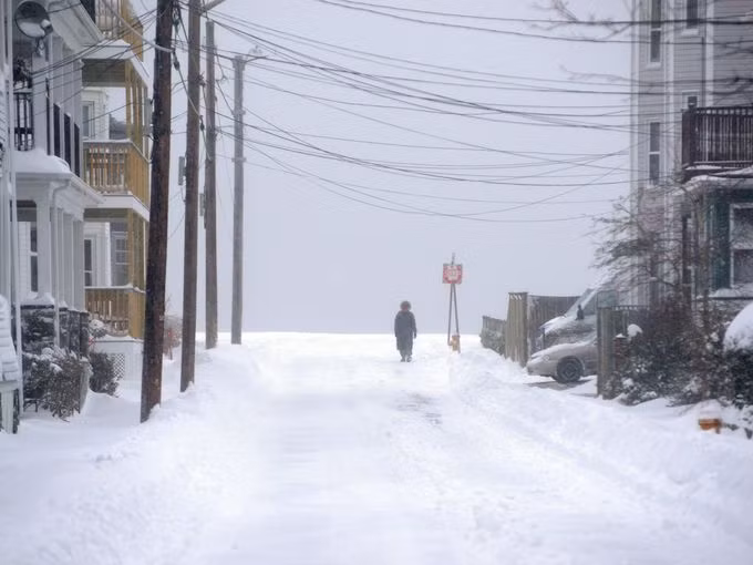 Người phụ nữ đi bộ trên con đường phủ đầy tuyết trắng sau một đêm tuyết rơi dày đặc.