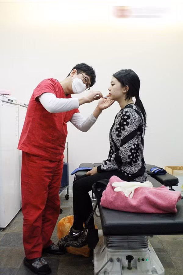 Bác sĩ bắt đầu vẽ những đường cần tiêm trên khuôn mặt Hạt Mít, nhiều nhất là hai vùng má và bọng cằm.