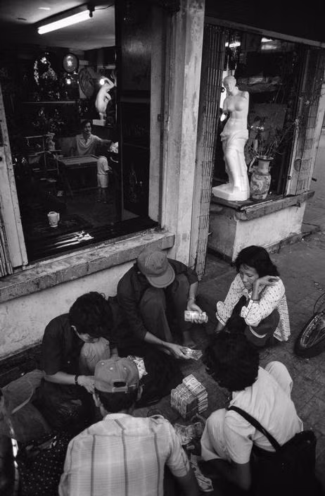 Đếm tiền lẻ trên vỉa hè Sài Gòn, 1988. Ảnh: Philip Jones Griffiths.