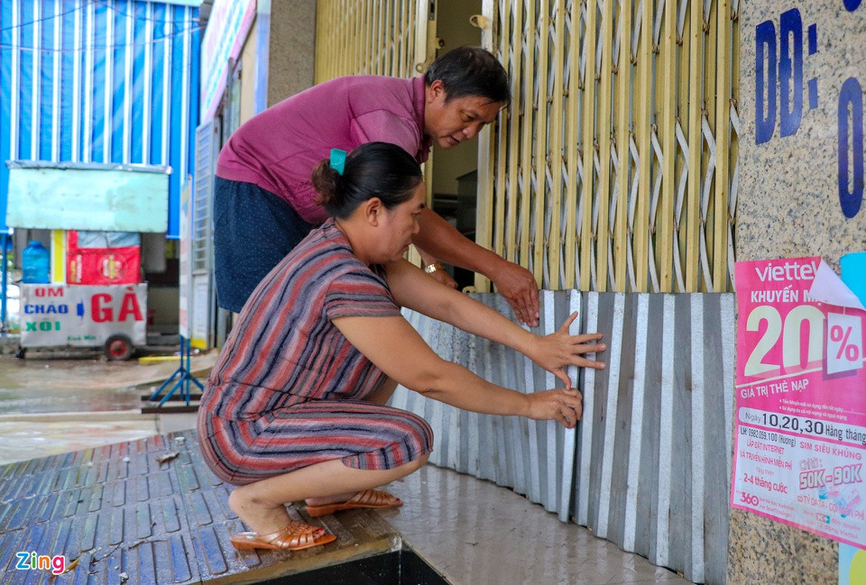 Tại đường Tôn Đức Thắng, phường An Sơn, vợ chồng ông Huỳnh Tấn Ánh dùng các tấm tôn chắn ngang cửa để tránh nước bắn vào nhà. "Mực nước bây giờ cũng sắp vào nhà rồi, tôi lo ngại ôtô đi qua tạo sóng đánh hư hỏng vật dụng. Nếu cứ mưa thế này, đến tối, nước sẽ vào nhà", ông Ánh nói.