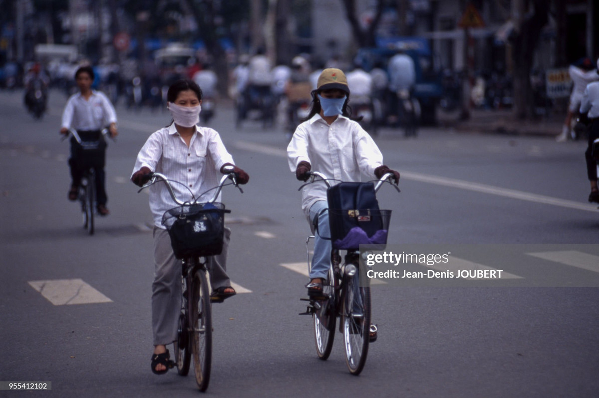 Hai cô gái đeo khẩu trang đạp xe trên đường.