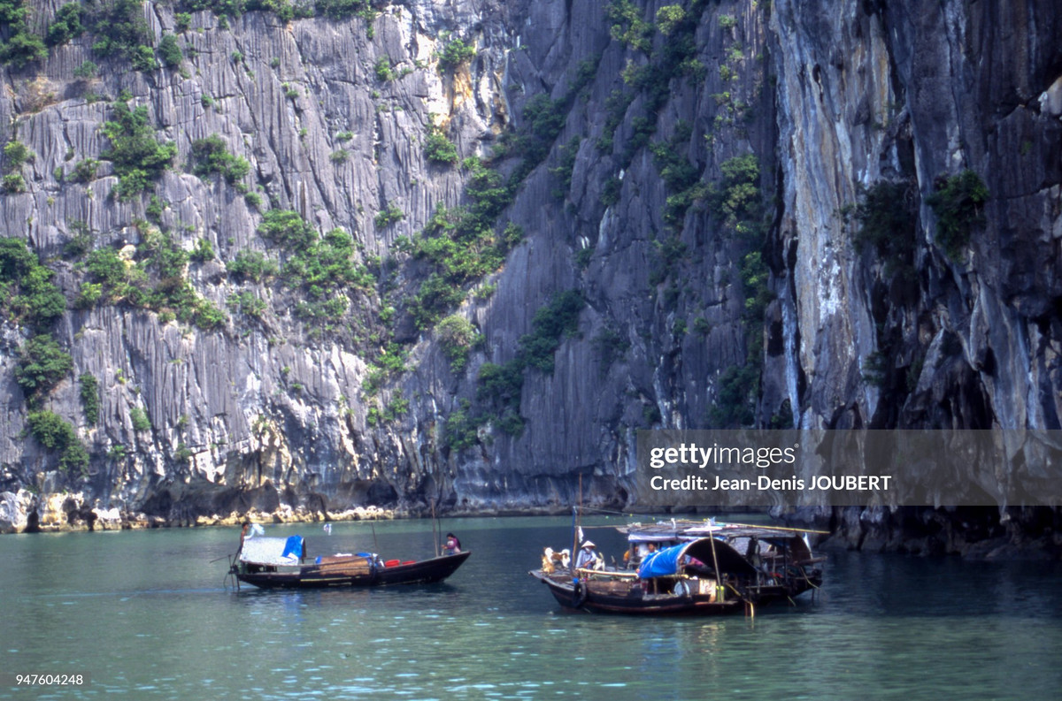Những con thuyền nhỏ bên vách đá vôi kỳ vĩ ở vịnh Hạ Long.