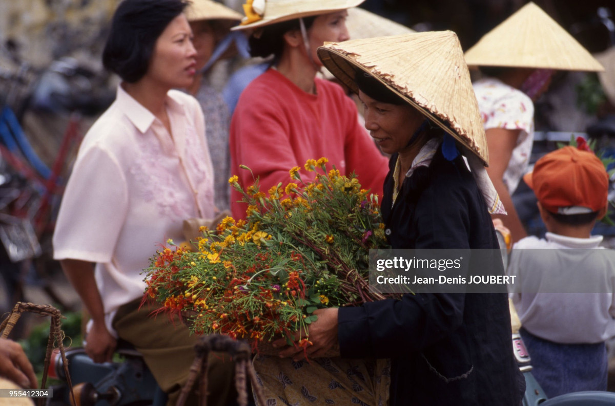 Người phụ nữ ôm bó hoa tươi ra chợ bán.