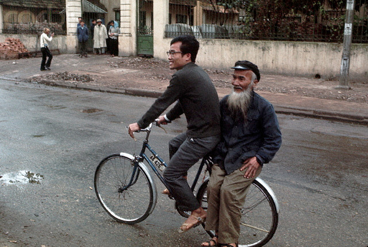 Chàng trai đèo cụ già bằng xe đạp trên đường phố Hà Nội.