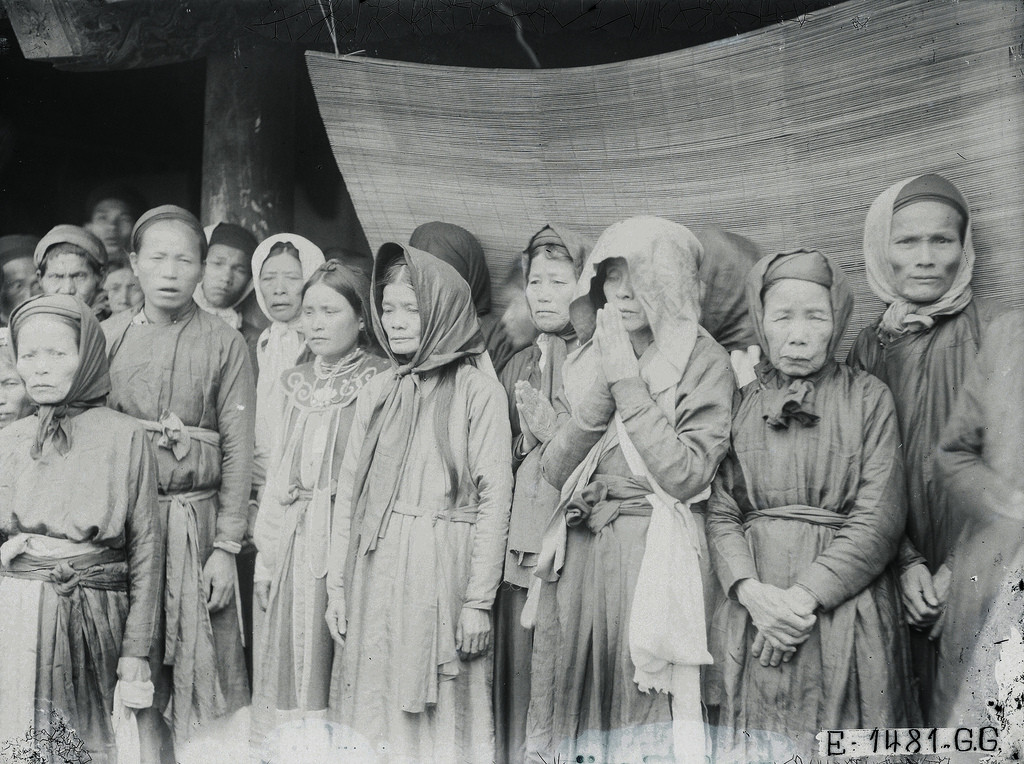 Một cụ bà chắp tay cầu nguyện trước đám rước kiệu.