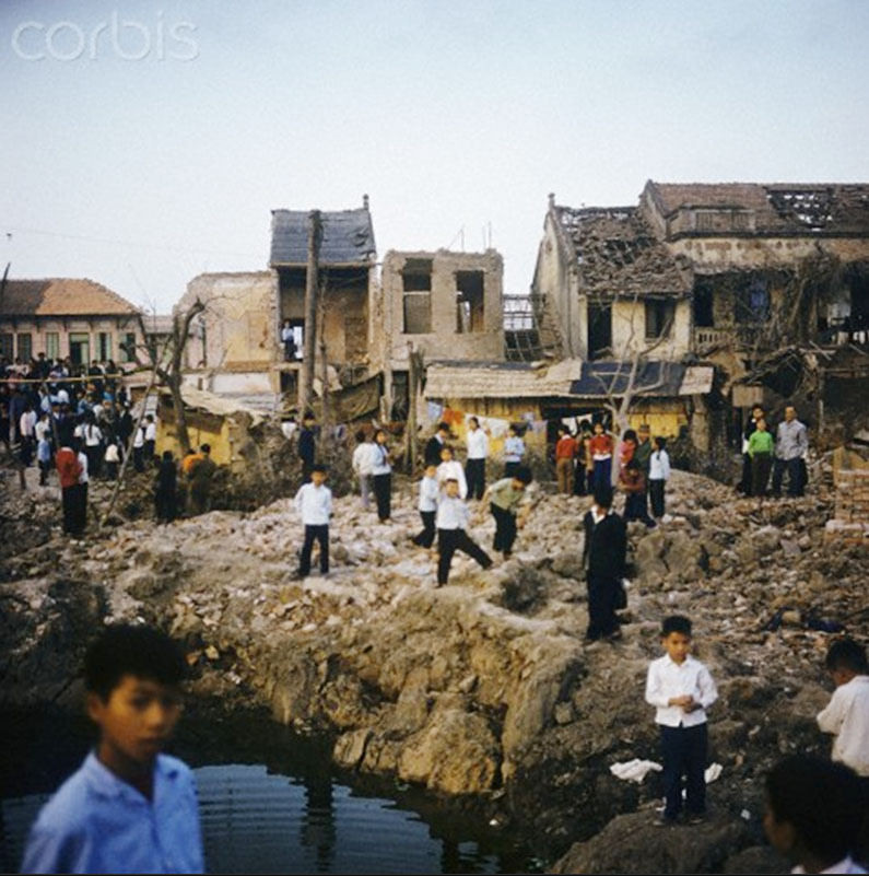 Các học sinh tiểu học đứng ngoài một ngôi trường trên con phố bị hủy diệt.