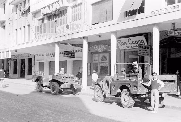 Xe quân sự Pháp đỗ trước các cửa hàng trên phố Paul Bert.