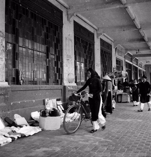 Một người phụ nữ dắt xe đi mua hàng trên vỉa hè phố Paul Bert .