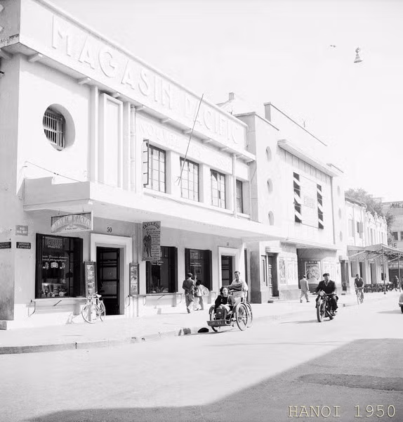 Tòa nhà Magasin Pacific trên phố Paul Bert (Tràng Tiền) với một dãy cửa hàng may, hàng vải và tiệm chụp ảnh ở tầng 1.