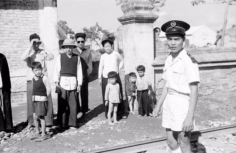 Một cảnh sát và những người dân đứng bên đường tàu.