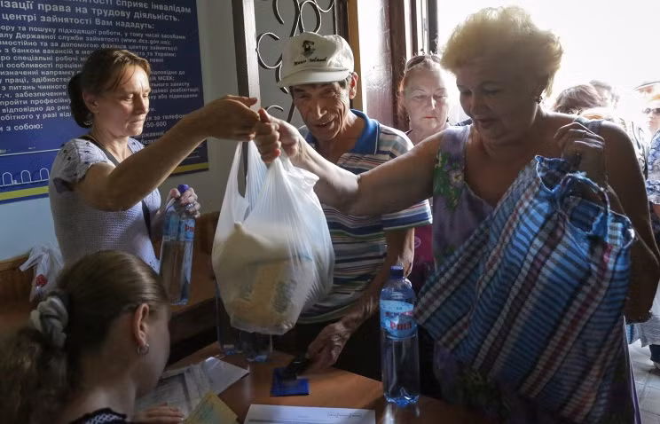 Người dân vùng chiến sự xếp hàng chờ nhận đồ cứu trợ.