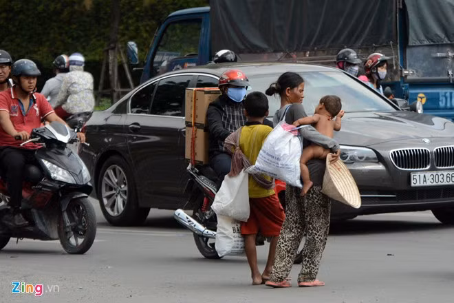 Tiếp xúc với một phụ nữ nói lơ lớ tiếng Việt, chúng tôi được biết những người này vừa từ Campuchia sang Việt Nam được hai ngày. Trong ảnh: Một phụ nữ và 2 trẻ nhỏ đi từ đường An Dương Vương tới ngã tư Nguyễn Trãi - Nguyễn Văn Cừ với những chiếc túi đựng đồ đạc còn mới dùng để xin ăn.