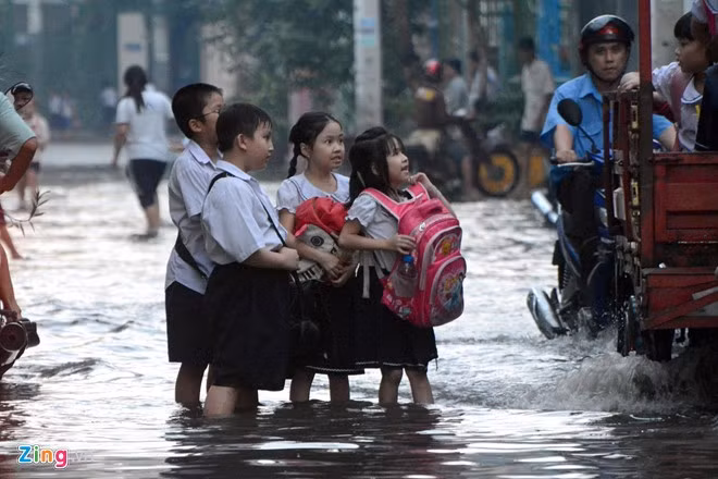 Nhiều học sinh khác không được phụ huynh đưa đón đành lội bì bõm nhìn các bạn may mắn hơn mình.