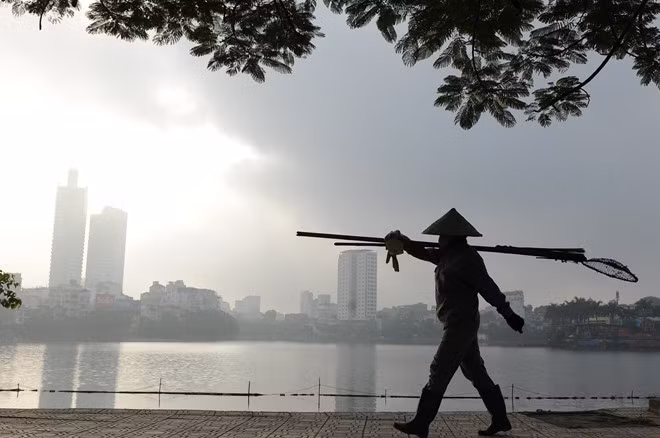 Chị công nhân vớt rác thong thả đi trong ánh bình minh.