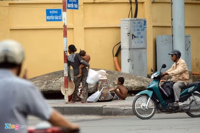Tại giao lộ Nguyễn Trãi - Nguyễn Văn Cừ (quận 1 và 5), một nhóm gồm hai phụ nữ mang theo 4 đứa trẻ ngồi bên cột đèn tín hiệu giao thông, lượn lờ quanh khu vực để xin tiền người đi đường.