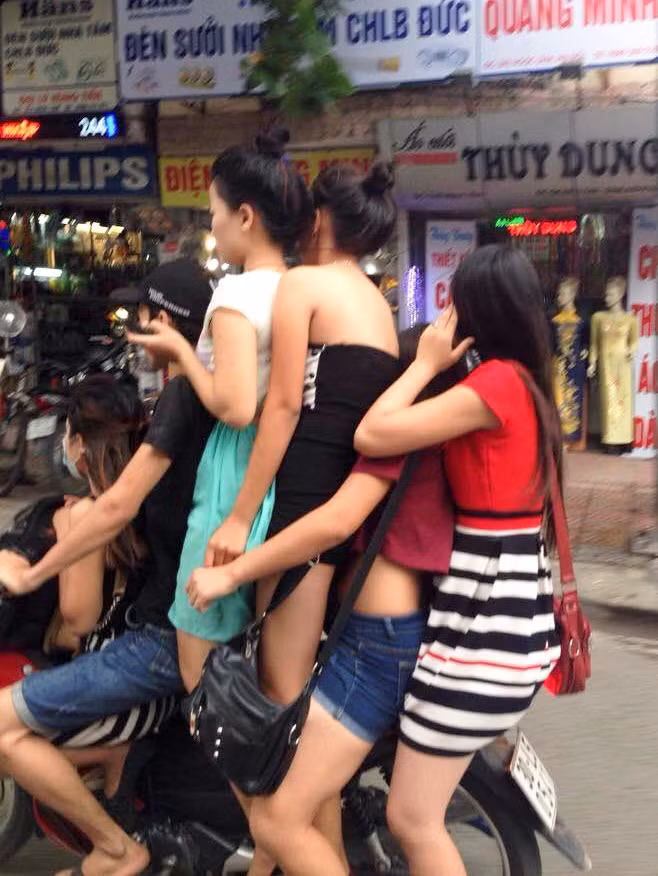 Một xế ôm đội mũ mềm kẹp thêm 5 cô gái ăn mặc hở hang, đứng cả lên xe máy phóng tốc độ cao khá nguy hiểm.
