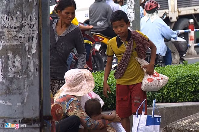 Nhóm tập trung tại ngã tư để xin ăn. Người dân cho biết, 2 ngày qua xuất hiện hai người đàn ông đi xe máy chở phụ nữ và trẻ nhỏ tới rồi đứng quan sát từ sáng đến tối.