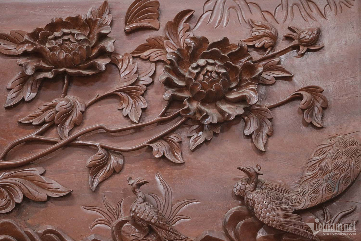 Các đế cột được đúc bằng đồng nguyên chất với tổng khối lượng 3,5 tấn. Nhà sàn có lan can bao quanh mặt trước và mặt sau, 15 bậc cầu thang lên xuống của 2 cửa chính với ý nghĩa thể hiện sự tinh tế quan điểm về vũ trụ, âm dương ngũ hành và nhân - sinh - quan cao đẹp. Họa tiết trên gỗ được chạm trổ nổi bật như một tác phẩm 3D. Ảnh: Nhị Tiến