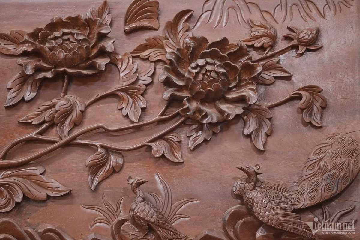 Các đế cột được đúc bằng đồng nguyên chất với tổng khối lượng 3,5 tấn. Nhà sàn có lan can bao quanh mặt trước và mặt sau, 15 bậc cầu thang lên xuống của 2 cửa chính với ý nghĩa thể hiện sự tinh tế quan điểm về vũ trụ, âm dương ngũ hành và nhân - sinh - quan cao đẹp. Họa tiết trên gỗ được chạm trổ nổi bật như một tác phẩm 3D. Ảnh: Nhị Tiến