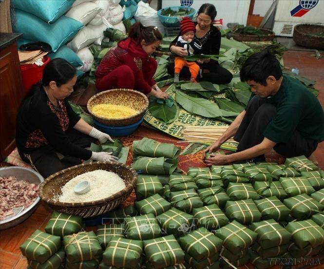 Cả nhà quây quần gói bánh chưng, thể hiện sự sum vầy, ấm áp và đoàn tụ trong ngày tết cổ truyền. Ảnh: Lâm Khánh/TTXVN