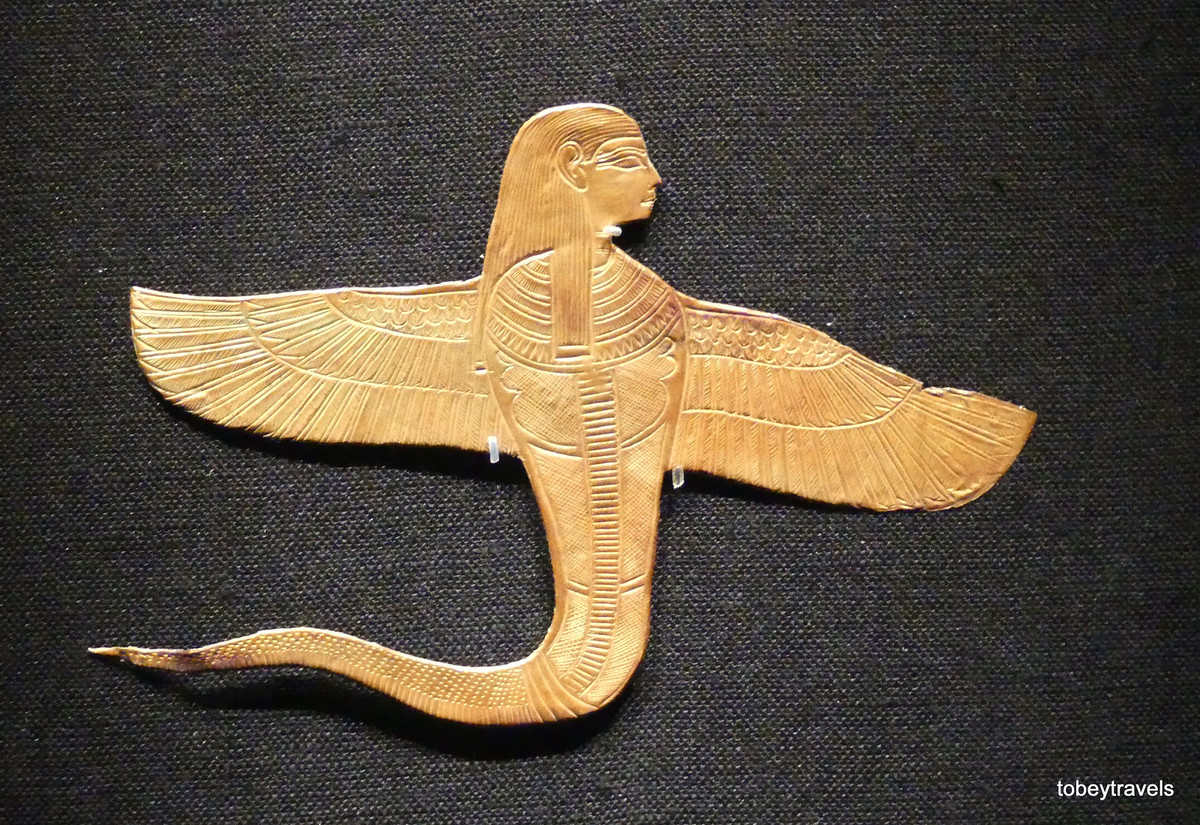 Bùa hình thần Uraeus với đầu người và có cánh. Trong tín ngưỡng Ai Cập, Uraeus là một biểu tượng của chủ quyền, quyền lực hoàng gia và thần thánh. Dạng thường gặp của vị thần này là một con rắn hổ mang.