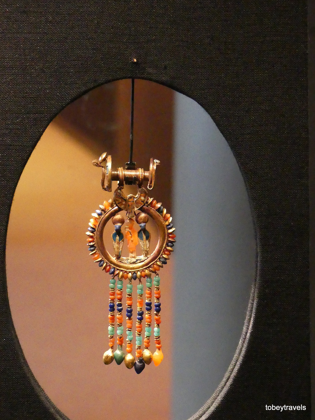 Khuyên tai bằng vàng và đá quý có hình Tutankhamun giữa hai con rắn hổ mang.