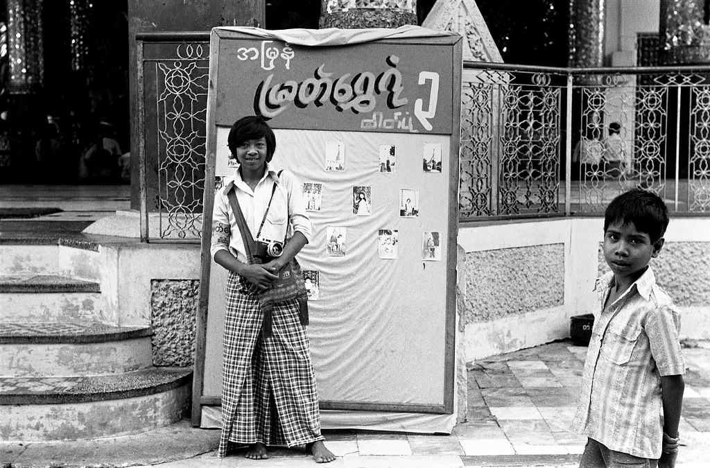 Phó nháy trẻ tuổi bên tấm bảng dán những tấm ảnh lưu niệm do mình chụp.