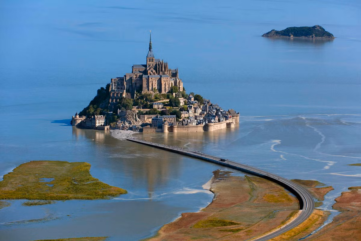 Trước kia Mont Saint Michel được nối với đất liền bằng một cây cầu nhỏ, khi thủy triều lên thì cầu cũng biến mất. Đến năm 1879, một con đường đắp cao được xây dựng để thay thế cho chiếc cầu này. Ảnh: Le Monde.