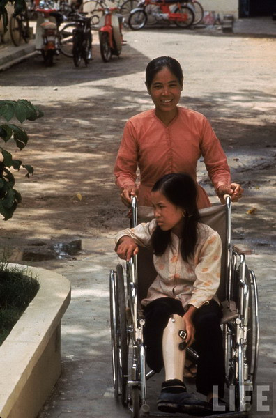 Một ngày sau, mẹ Tròn đến gặp em trong bệnh viện. Họ được sĩ quan Mỹ đưa khoản tiền tương đương 35 USD để bồi thường cho “tai nạn” xảy ra trong rừng. Gần 1/3 của số tiền này ngay sau đó được dùng để trả cho việc truyền máu của bệnh viện. Ảnh: Tròn và mẹ tại trung tâm phục hồi chức năng.