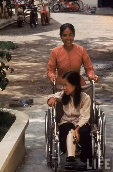 Một ngày sau, mẹ Tròn đến gặp em trong bệnh viện. Họ được sĩ quan Mỹ đưa khoản tiền tương đương 35 USD để bồi thường cho “tai nạn” xảy ra trong rừng. Gần 1/3 của số tiền này ngay sau đó được dùng để trả cho việc truyền máu của bệnh viện. Ảnh: Tròn và mẹ tại trung tâm phục hồi chức năng.