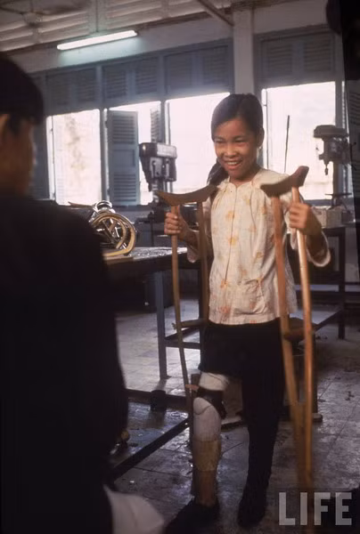 Lính Mỹ nhanh chóng đổ bộ xuống hiện trường và phát hiện ra rằng nạn nhân của họ là một ông già và hai bé gái. Họ đưa Tròn lên máy bay trực thăng và chở về bệnh viện ở Củ Chi. Ảnh: Tròn nhận chiếc chân giả của mình.