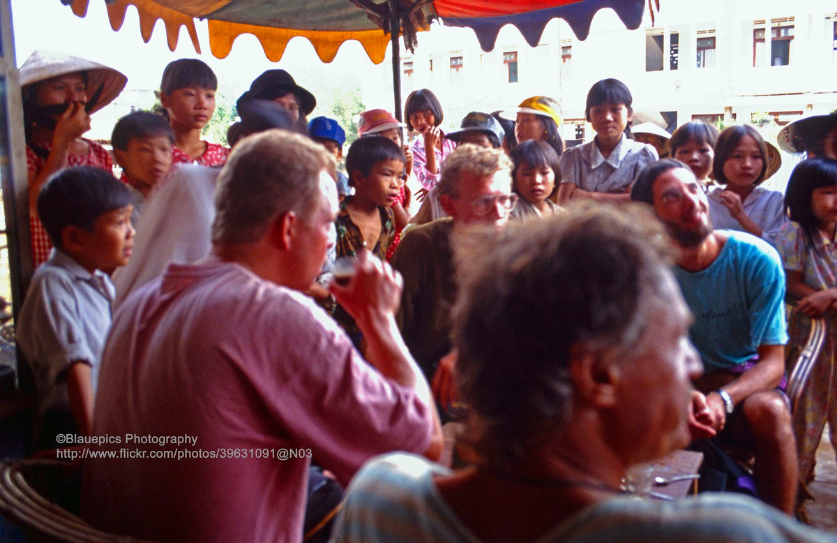 Các vị khách châu Âu thưởng thức cà phê ở Huế trước khi khởi hành tới Khu phi quân sự vĩ tuyến 17 ở Quảng Trị, 1993. Trẻ em địa phương rất tò mò khi thấy khách du lịch Tây - khá hiếm ở Huế thời điểm này - ngồi trên phố. Ảnh: Gunter Hartnagel / FLickr.