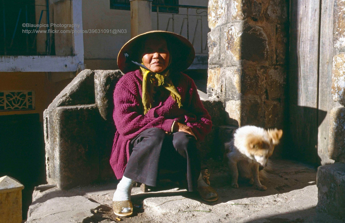 Cụ bà và chú chó sưởi nằng bên hiên ngôi nhà cổ.