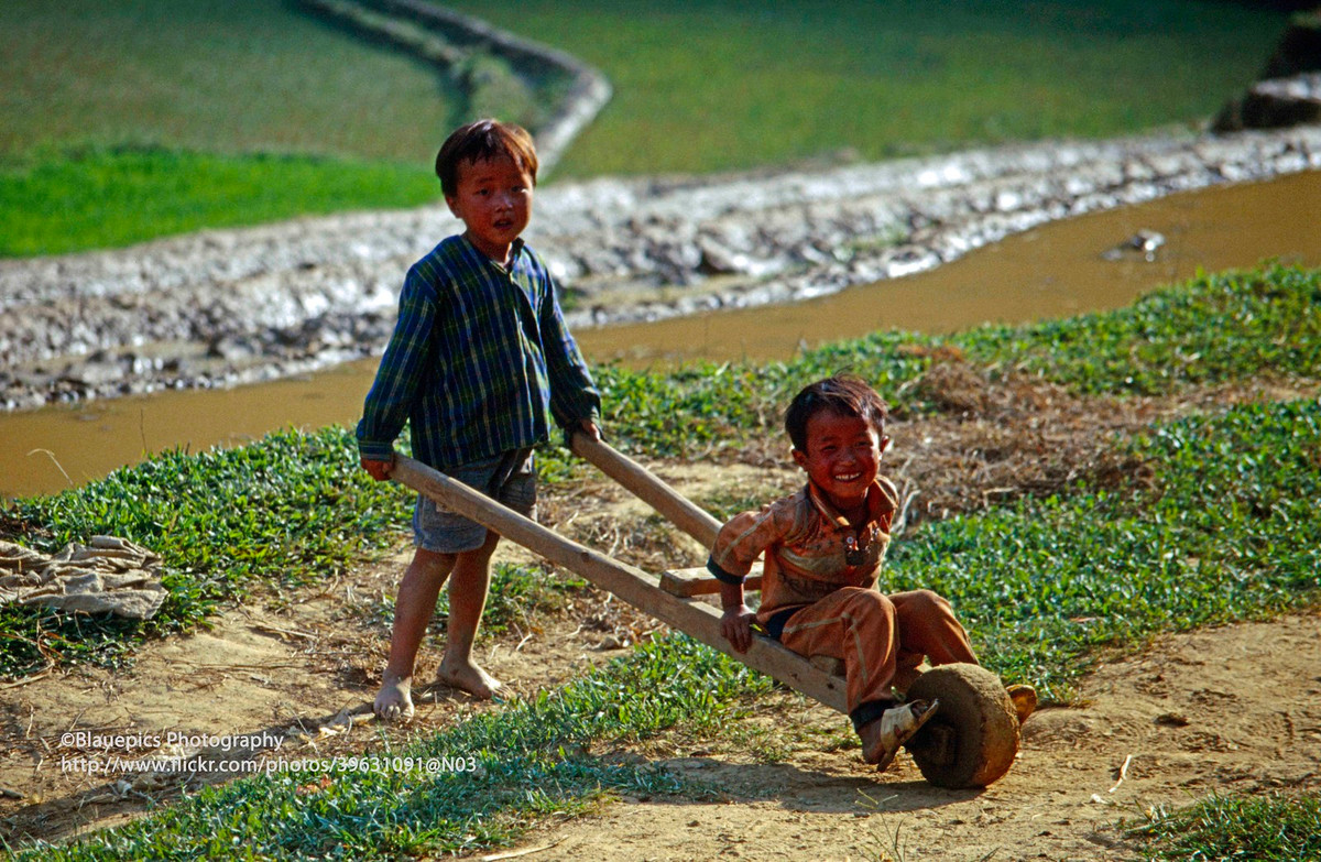 Hai chú bé Bản Phố chơi đùa với xe cút kít.