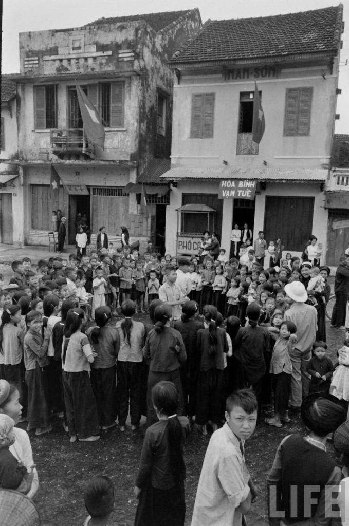 Người dân tụ họp bên một ngôi nhà treo biểu ngữ “Hòa bình vạn tuế”.