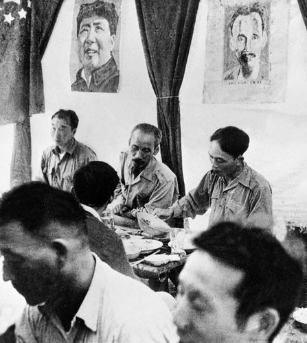 Chủ tịch Hồ Chí Minh (giữa) và Đại tướng Võ Nguyên Giáp (phải) trò chuyện trong bữa ăn vào khoảng năm 1946. Ảnh AP