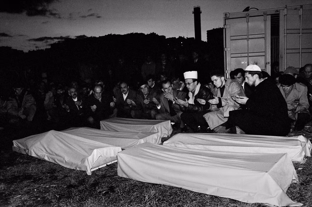 Người dân cầu nguyện bên quan tài của các trẻ em và người lớn vừa thiệt mạng trong vụ pháo kích một trường học ở Sarajevo, 1993. Theo truyền thống Hồi giáo, người chết phải được chôn trước khi mặt trời lặn. Ảnh: A. Abbas/ magnum Photos.