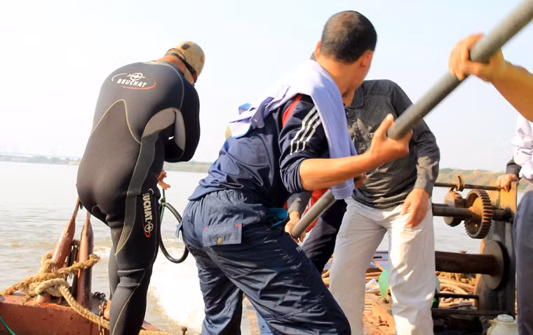 Thợ lặn bắt đầu xuống vị trí mà đặt ống thổi cát dưới đáy sông Hồng.