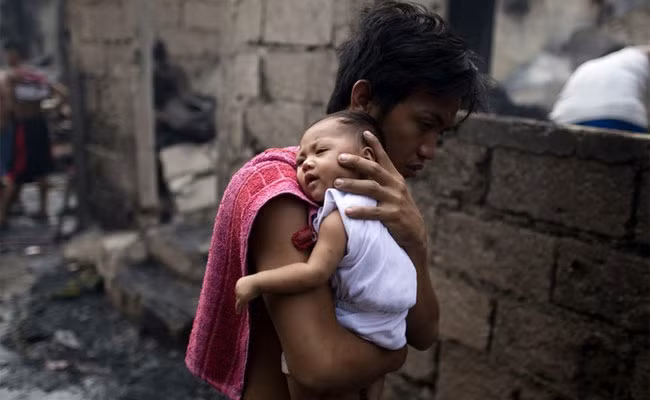 Người cha trẻ tuổi đang bế cậu con trai nhỏ của mình tới khu nhà tạm sau khi một trận hỏa hoạn vào giữa đêm thiêu rụi khoảng 200 ngôi nhà tại khu ổ chuột ở thủ đô Manila, Philippines.