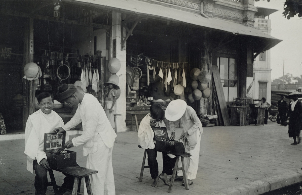 Hai người thợ làm tóc sửa soạn đồ nghề trước khi phục vụ hai cậu bé, miền Bắc Việt Nam năm 1934.