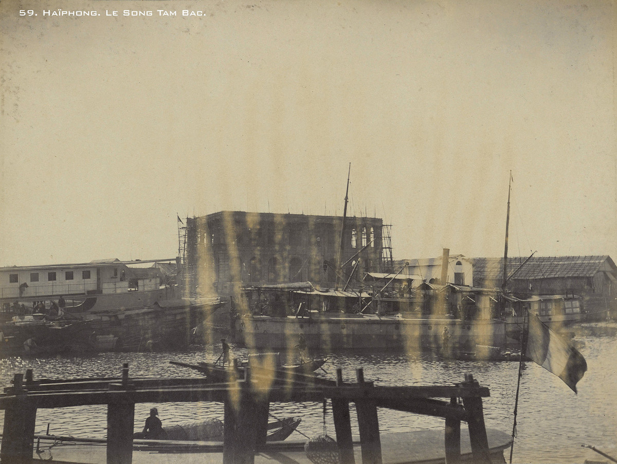 Một tòa nhà kiểu phương Tây đang được xây dựng bên bờ sông Tam Bạc, cạnh đó là một con tàu hơi nước.