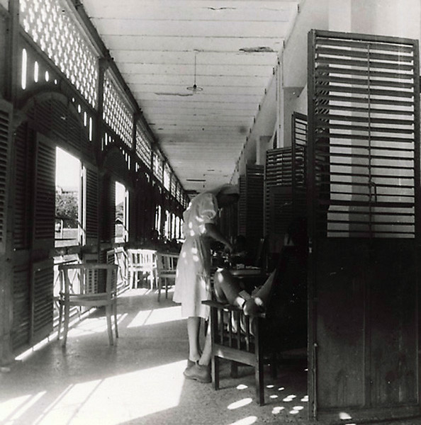 Một quân nhân được y tá chăm sóc tại hành lang của Bệnh viện Grall năm 1947. Sau ngày thống nhất đất nước, bệnh viện được chuyển giao cho chính quyền cách mạng.